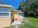 Yellow home exterior featuring a small white door sunroom in a grassy backyard at 844 67Th S St, South Pasadena, FL 33707