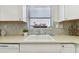 Close-up of kitchen sink and counter with mosaic backsplash and window with flower box at 854 Sky Loch N Dr, Dunedin, FL 34698