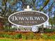 Welcome to Downtown Dunedin sign with colorful flowers and foliage in front of a black iron fence at 854 Sky Loch N Dr, Dunedin, FL 34698