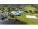 Aerial view of community pool with deck chairs and lakeshore beach volleyball at 5754 Sweet William Ter, Land O Lakes, FL 34639