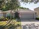 Charming single-story home with a gray exterior, lush landscaping, and an attached two-car garage at 5754 Sweet William Ter, Land O Lakes, FL 34639