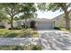 Charming single-story home with a gray exterior, lush landscaping, and an attached two-car garage at 5754 Sweet William Ter, Land O Lakes, FL 34639