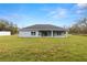 Rear view of the home showcasing the covered patio and expansive backyard with plenty of green space at 10262 Maybird Ave, Weeki Wachee, FL 34613