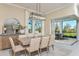 Bright dining area with a modern chandelier, large windows overlooking the backyard, and access to an outdoor patio space at 11423 Shoreline Trl, Parrish, FL 34219