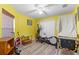 Bright bedroom featuring yellow walls, ceiling fan, wood-look floors and exercise equipment at 11449 Crestlake Village Dr, Riverview, FL 33569