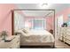 Bedroom features a four-poster bed, neutral bedding, and soft pink walls for a cozy retreat at 11449 Crestlake Village Dr, Riverview, FL 33569