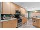 Well-lit kitchen with stainless steel appliances, light wood cabinets, and stylish gray flooring at 11449 Crestlake Village Dr, Riverview, FL 33569