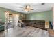 Open-concept living room featuring a ceiling fan, laminate floors, neutral paint, and access to the backyard at 11449 Crestlake Village Dr, Riverview, FL 33569
