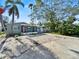 Quaint single-story home with screened in porch, red door, and mature landscaping at 1214 Bay Shore Blvd, Indian Rocks Beach, FL 33785