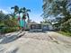Charming single-story home with palm trees and a welcoming front porch and red door at 1214 Bay Shore Blvd, Indian Rocks Beach, FL 33785
