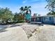 A charming single-story home featuring a red front door, screened in porch, and serene landscaping at 1214 Bay Shore Blvd, Indian Rocks Beach, FL 33785