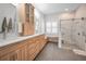Modern bathroom with wood cabinets, double vanity, marble floors, and a walk-in shower with glass door at 15229 Wind Whisper Dr, Odessa, FL 33556