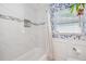 The bathroom features white marble tiles, a shower, a window, and a toilet at 1648 Arbor Dr, Clearwater, FL 33756