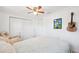 This bedroom features a ceiling fan, closet, a framed painting, and a guitar at 1648 Arbor Dr, Clearwater, FL 33756