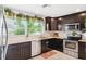 Kitchen with dark cabinets, granite countertops, stainless steel appliances, and greenery on window at 1648 Arbor Dr, Clearwater, FL 33756