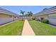Exterior view of a well-kept community featuring landscaped grounds, a grassy courtyard, and palm trees at 1802 Bedford Ter # 187, Sun City Center, FL 33573