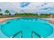 Large community pool with steps and railings with chairs and shade umbrellas on the pool deck at 18796 Obregan Dr, Spring Hill, FL 34610