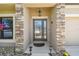 Covered front porch with stone columns, decorative glass door, and well-manicured landscaping at 18796 Obregan Dr, Spring Hill, FL 34610