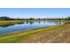 Scenic view of a large pond in the backyard, surrounded by lush grass and neighboring houses at 18796 Obregan Dr, Spring Hill, FL 34610
