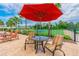 Relaxing poolside seating under a shade umbrella with community tennis and basketball courts in view at 18796 Obregan Dr, Spring Hill, FL 34610