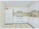 Well-lit kitchen with white cabinets and appliances, tiled flooring, and ample counter space at 1881 N Hercules Ave # 1303, Clearwater, FL 33765