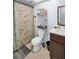 Bathroom featuring a floral shower curtain, a shelf unit, wood floors, a white toilet, and a brown sink vanity at 2366 Covington Dr, Clearwater, FL 33763