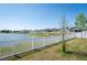Picturesque backyard featuring a lake view, beautifully framed by a white fence at 35853 Buttonweed Trl, Zephyrhills, FL 33541