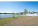 Lush backyard offering a peaceful lake view, enhanced by a classic white fence at 35853 Buttonweed Trl, Zephyrhills, FL 33541