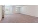 Bright, carpeted bedroom featuring ample natural light and a door leading to other parts of the house at 35853 Buttonweed Trl, Zephyrhills, FL 33541