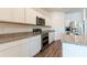 Modern kitchen features white cabinets, stainless steel appliances, granite counters, and wood-look flooring at 35853 Buttonweed Trl, Zephyrhills, FL 33541