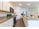 Modern kitchen features white cabinets, stainless steel appliances, granite counters, and wood-look flooring at 35853 Buttonweed Trl, Zephyrhills, FL 33541