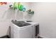 Modern laundry room with white washer and dryer, complemented by convenient overhead shelving at 35853 Buttonweed Trl, Zephyrhills, FL 33541