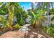 Private backyard oasis with lush tropical plants, stone pathway, and a charming white fence at 404 Danube Ave, Tampa, FL 33606