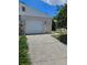 Home exterior with white garage door, number 414, and cracked driveway lined with manicured greenery at 414 Danube Ave, Tampa, FL 33606