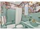 Vintage-style bathroom with green tile, patterned wallpaper, tub with shower, and gold fixtures at 420 48Th N St, St Petersburg, FL 33713
