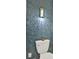 A powder room with textured tile accent wall with a modern wall sconce and updated toilet at 420 48Th N St, St Petersburg, FL 33713