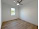 Bright, minimalist bedroom featuring light wood floors, a ceiling fan, and a large window at 5105 68Th N Way, St Petersburg, FL 33709