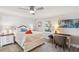 A sunlit bedroom featuring a ceiling fan and a cozy sitting area with a desk and lamps at 5240 Coquina Key Se Dr # B, St Petersburg, FL 33705