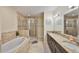 Elegant bathroom featuring a bathtub, a glass-enclosed shower, and dual sinks with granite countertops at 6822 Kissimmee St # 8-B, Tampa, FL 33616