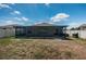 View of the backyard with a screened-in patio, lush green grass, and a fence surrounding the property at 7202 Ozello Trail Ave, Ruskin, FL 33573