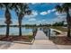 Scenic view of a lake with a wooden dock, surrounded by palm trees and lush landscaping, inviting for leisurely strolls at 7202 Ozello Trail Ave, Ruskin, FL 33573