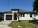 Modern home with a black garage door, neat landscaping, and freshly cut green grass at 7208 N Glen Ave, Tampa, FL 33614