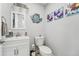 Cozy half-bath with white vanity, toilet, decor and stylish artwork at 750 Sand Pine Ne Dr, St Petersburg, FL 33703