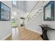 Bright foyer with staircase, white walls, wood floors, coat rack, and glass front door at 750 Sand Pine Ne Dr, St Petersburg, FL 33703
