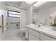 Clean, all-white bathroom featuring a shower-tub combo and a large mirror at 785 Hickory Ln, Palm Harbor, FL 34683