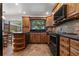 Traditional kitchen featuring warm wood cabinetry, black appliances, granite counters, and slate backsplash and tile flooring at 785 Hickory Ln, Palm Harbor, FL 34683