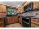 Bright kitchen featuring wood cabinetry, black appliances, granite countertops, and tile backsplash and flooring at 785 Hickory Ln, Palm Harbor, FL 34683