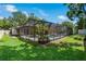 Exterior view of screened-in pool area surrounded by lush landscaping and a well-maintained lawn at 785 Hickory Ln, Palm Harbor, FL 34683