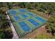 Aerial view of a community tennis court complex with multiple blue and green courts surrounded by lush trees at 785 Hickory Ln, Palm Harbor, FL 34683