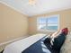 A bright bedroom with a window offering ocean views, featuring a ceiling fan and neutral wall colors at 8030 Manasota Key Rd, Englewood, FL 34223